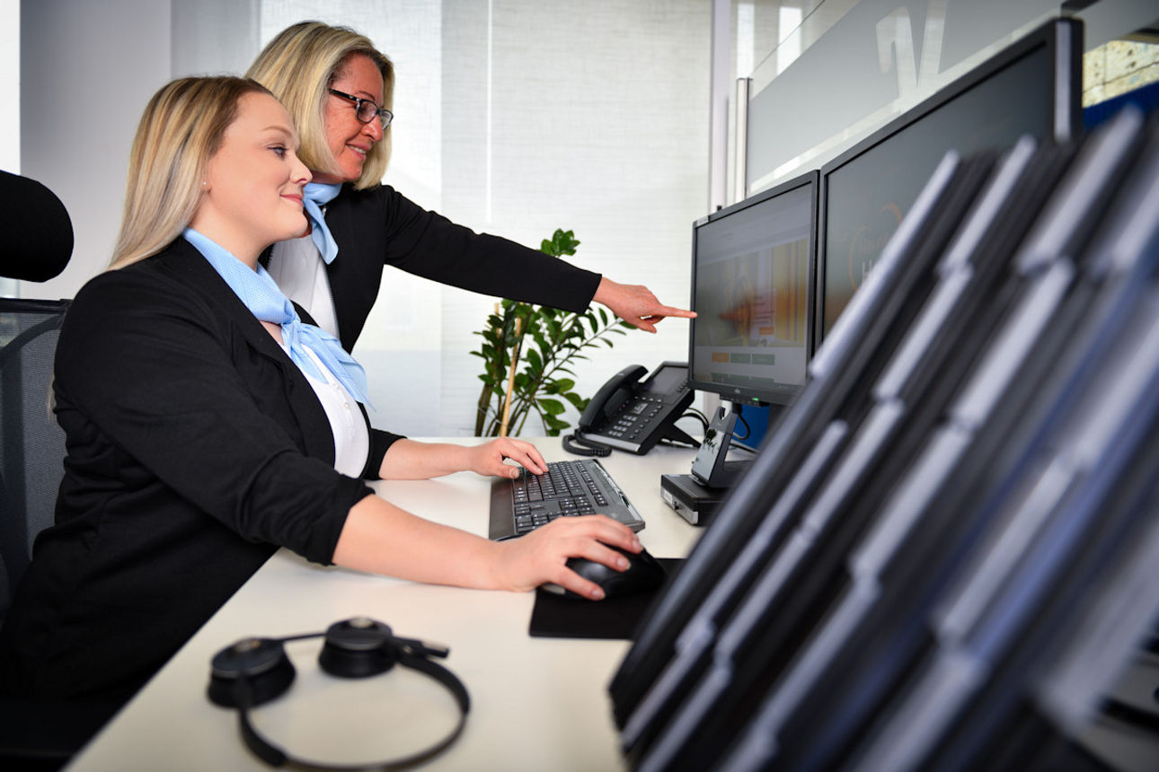 Mitarbeiterinnen der Bank blicken auf einen Bildschirm