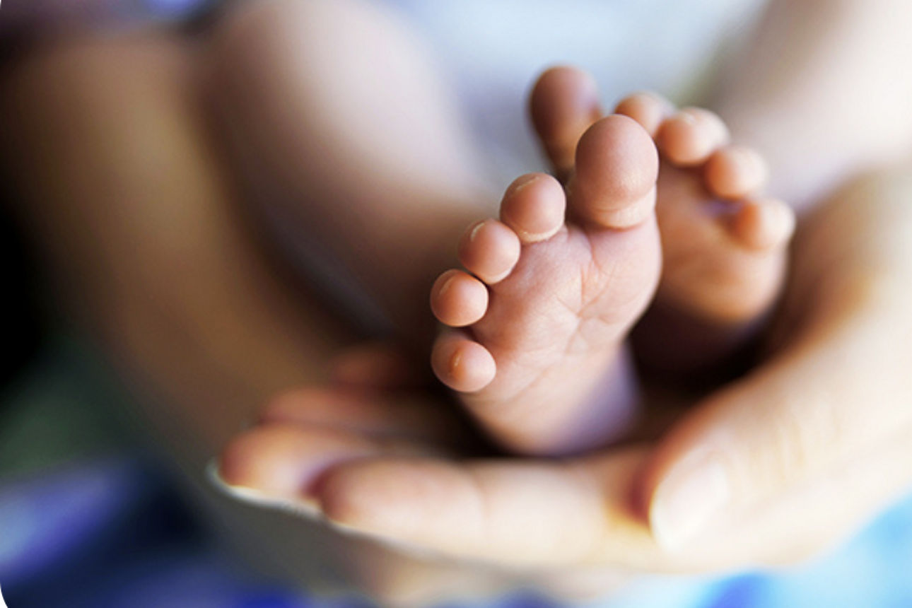 Füße eines Neugeborenen auf der Hand der Mutter