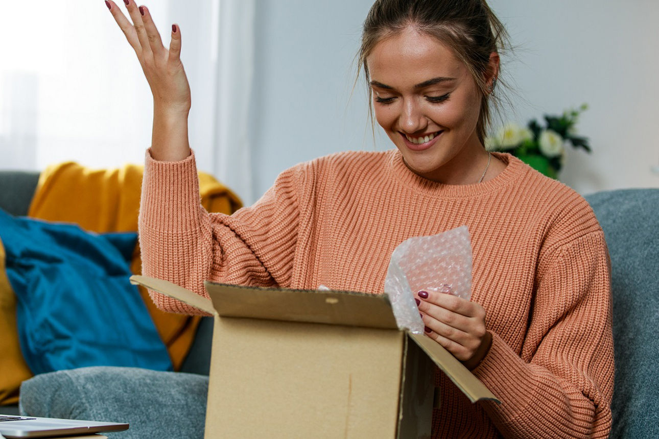 Lächelnde Frau, die ein offene Paket-Schachtel in den Händen hält
