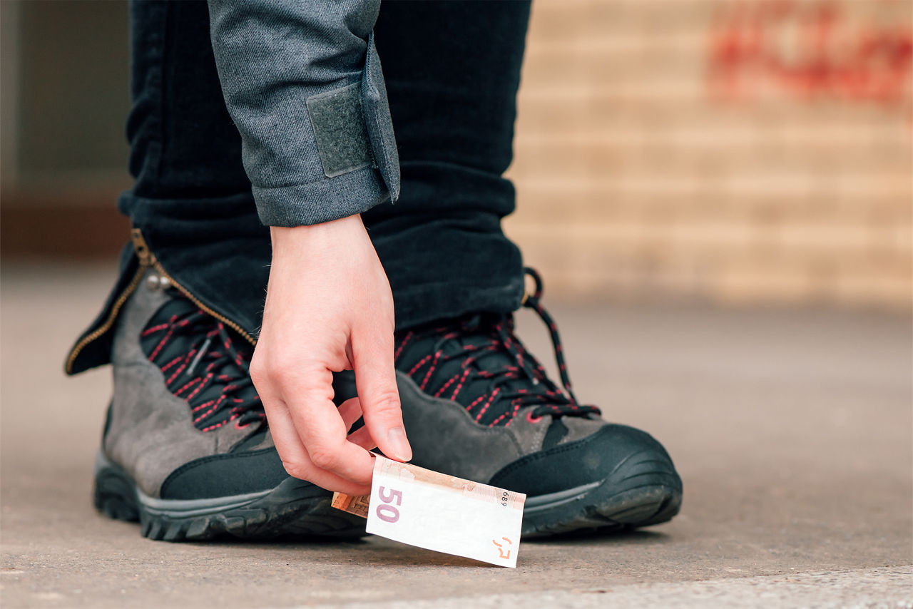 Eine Person hebt einen 50-Euro-Schein vom Boden auf.