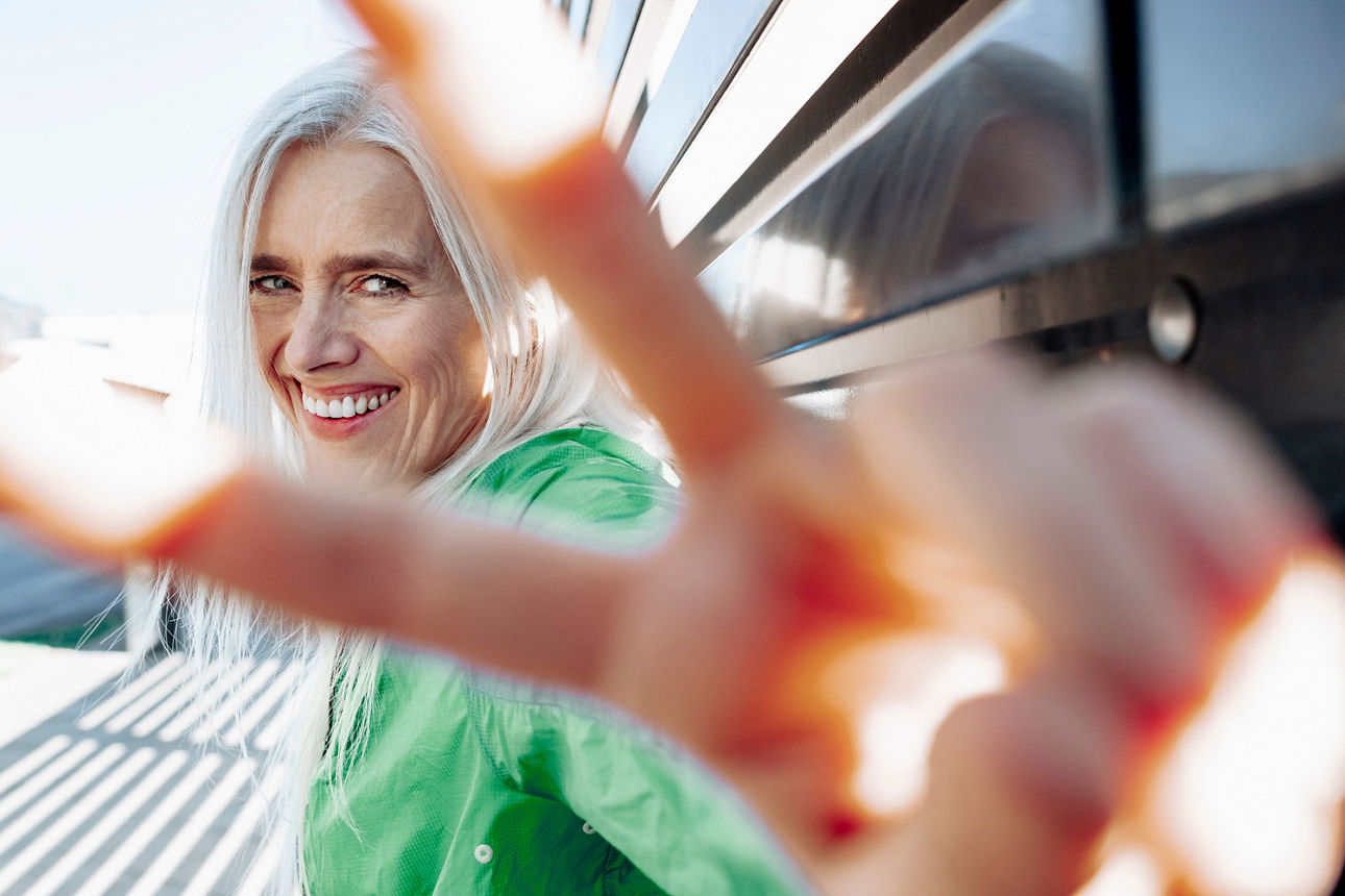 Eine Frau lächelt und zeigt das Victory-Zeichen
