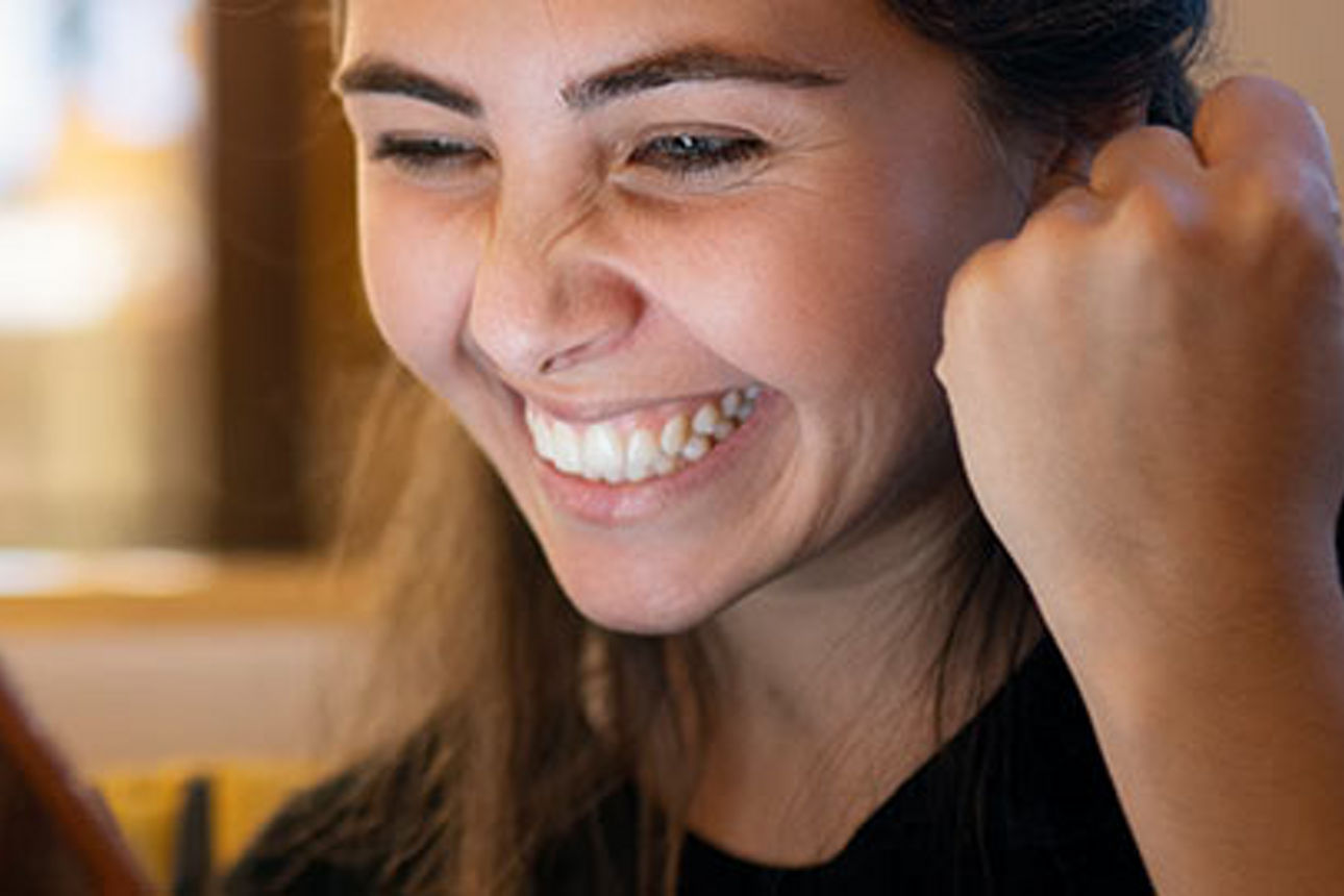Eine junge Frau mit langen dunklen Haaren sitzt in einem Café