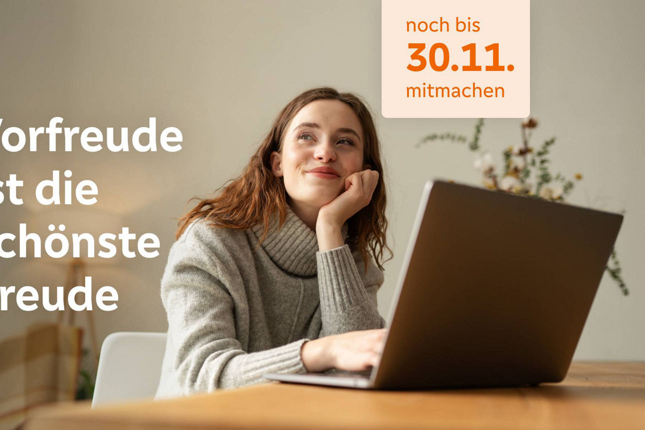 Junge Frau sitzt verträumt am Schreibtisch vor ihrem Laptop