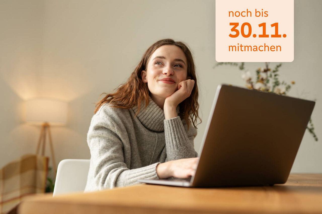 Junge Frau sitzt verträumt am Schreibtisch vor ihrem Laptop