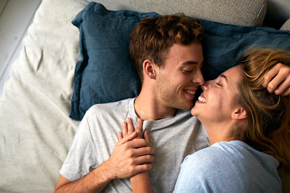 Eine Frau und ein Mann im Bett, die sich fast küssen