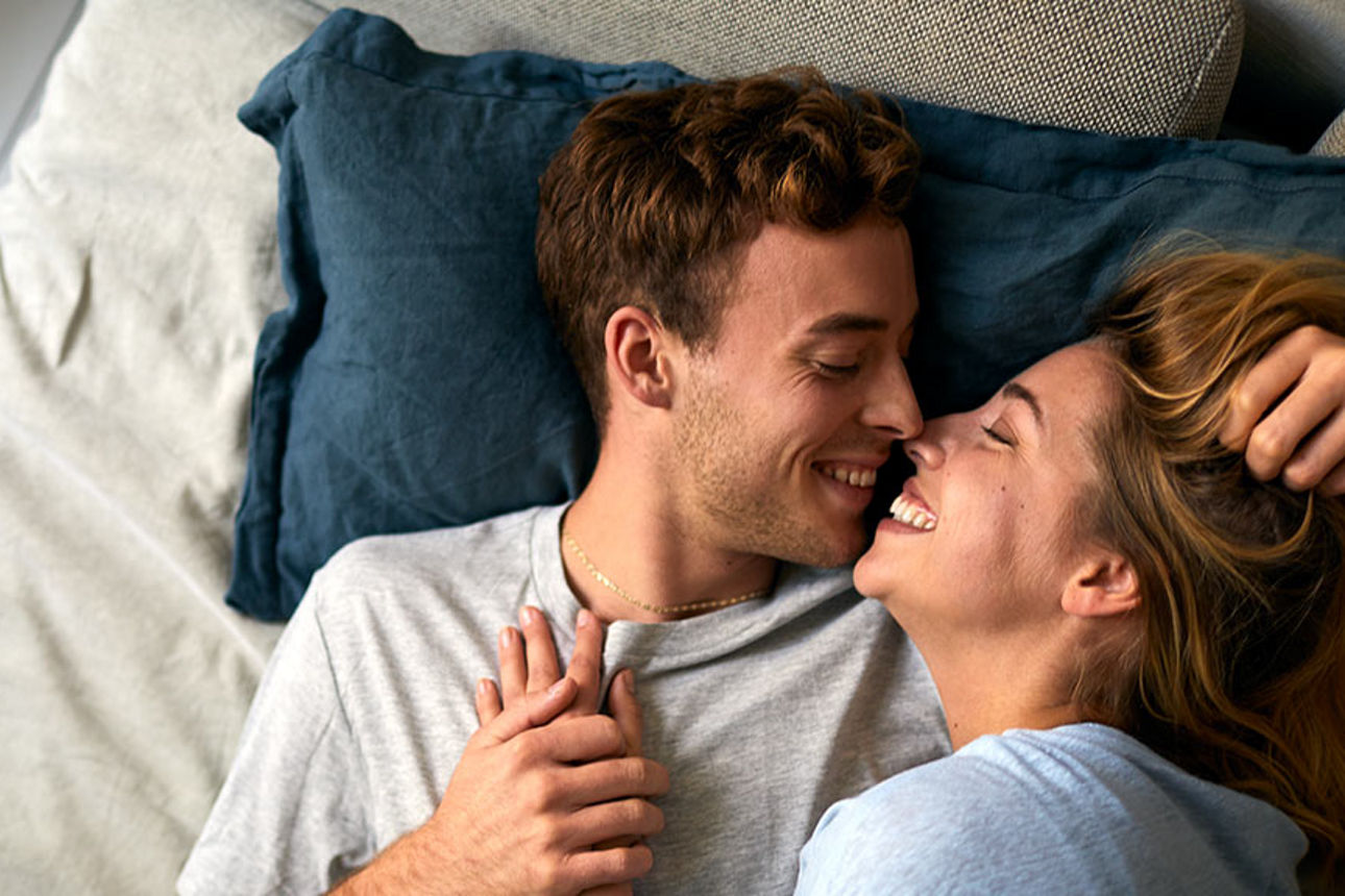 Eine Frau und ein Mann im Bett, die sich fast küssen