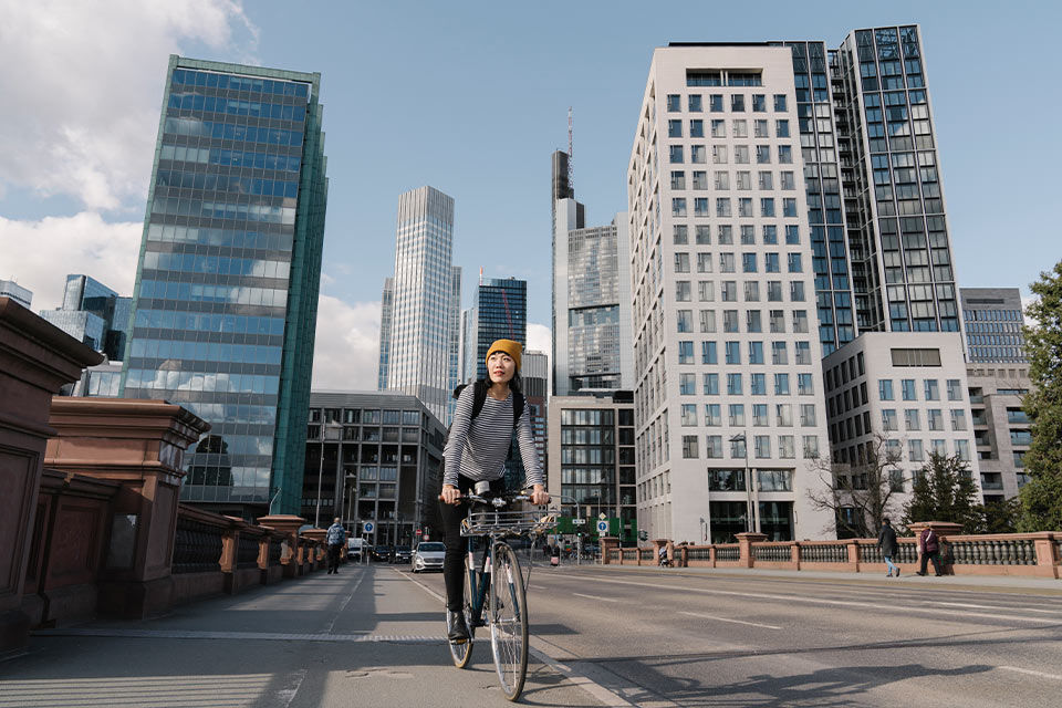 Junge Frau zwischen Hochäusern auf dem Rad