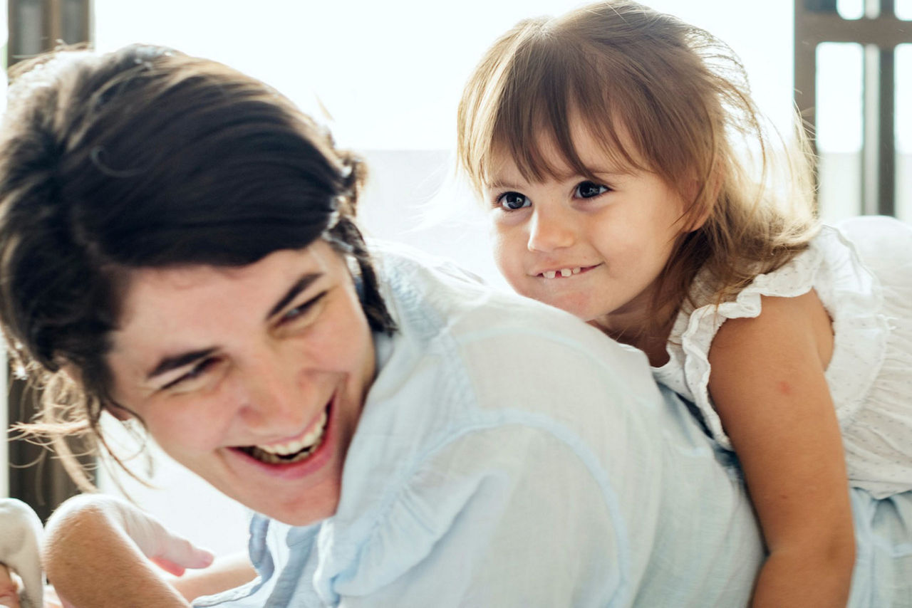 Mutter mit ihrer Tochter auf dem Rücken