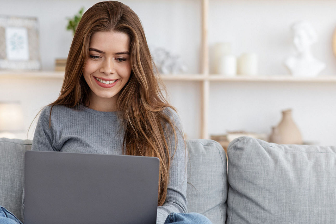 Frau mit Laptop auf Sofa