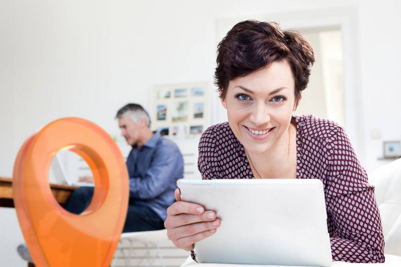 Frau liegt mit ihrem Laptop auf der Couch