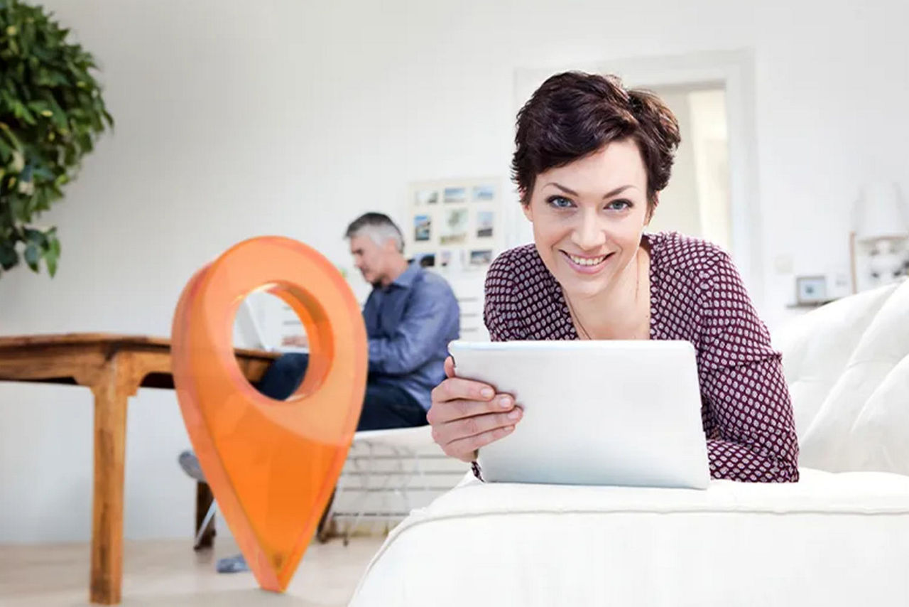 Frau liegt mit ihrem Laptop auf der Couch