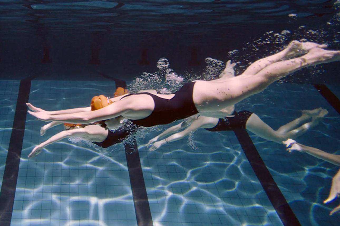 Schwimmerinnen die in ein Schwimbecken hinein springt.