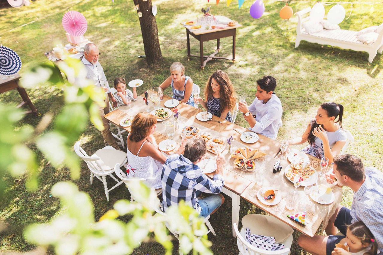 Mehrere Personen sitzen zusammen am Tisch im Garten