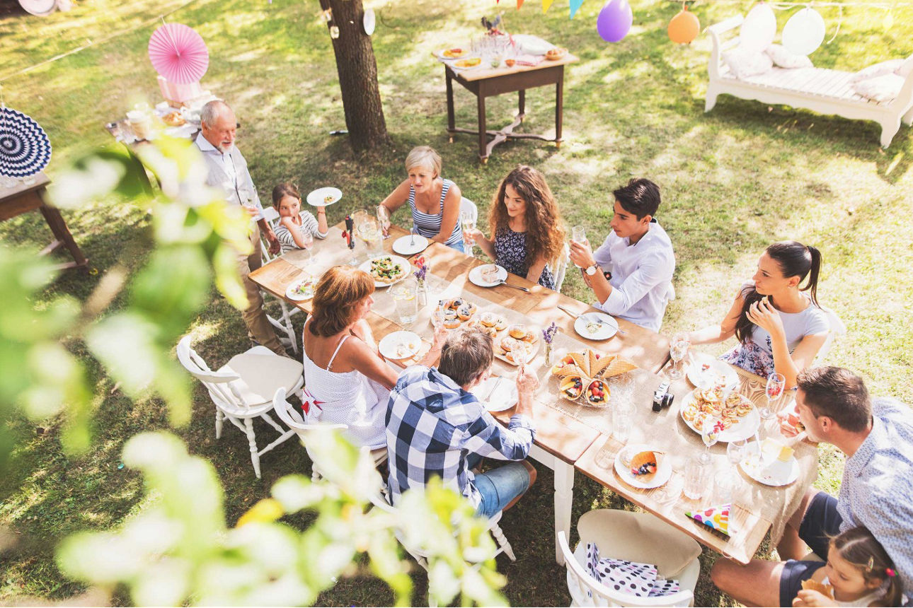 Mehrere Personen sitzen zusammen am Tisch im Garten