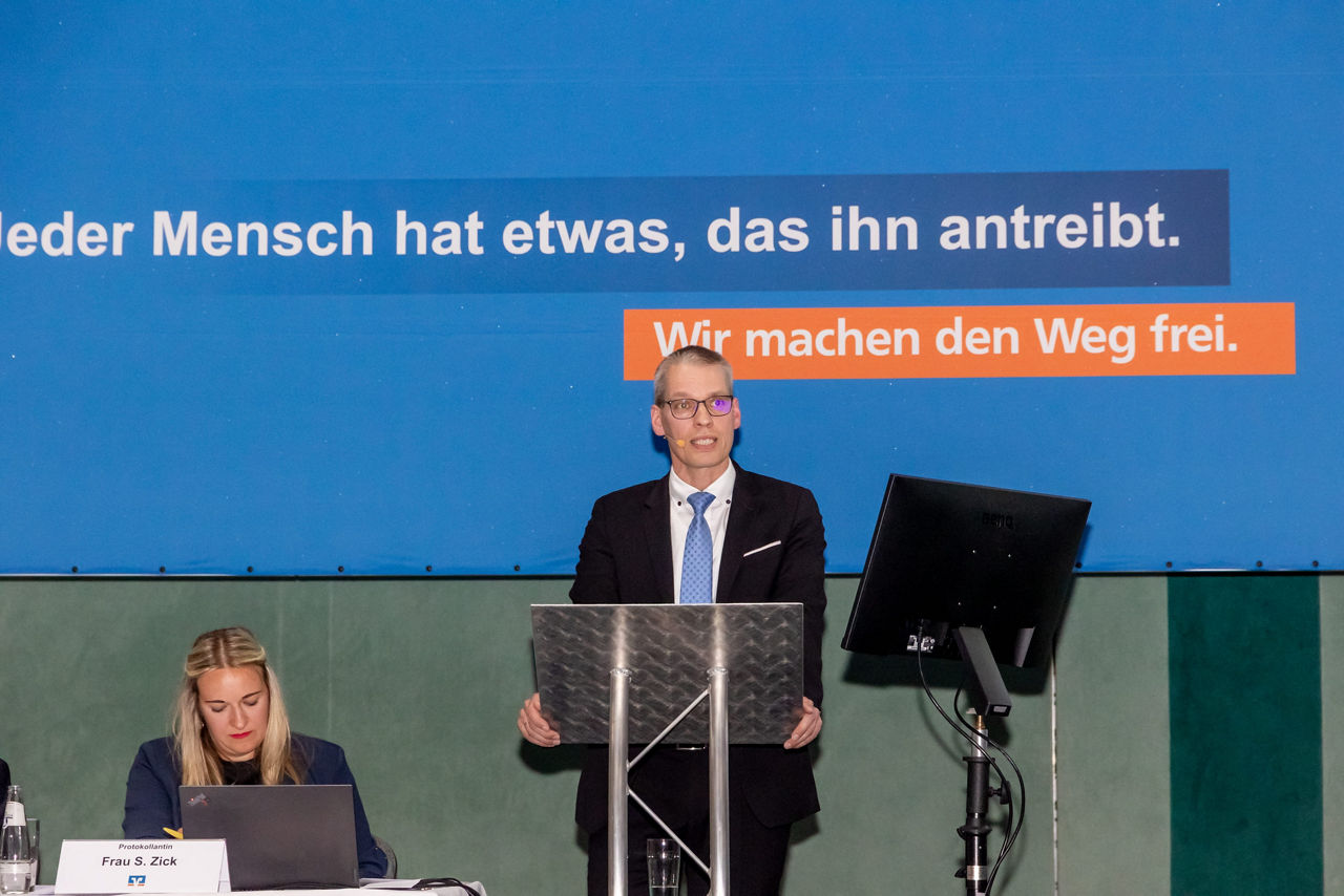 Ein Mann hält einen Vortrag vor einer Menschenmenge.