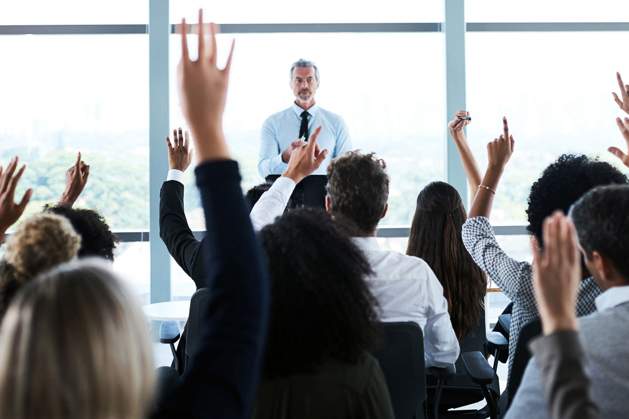 Ein Bild einer Generalversammlung bei der viele Menschen die Arme heben