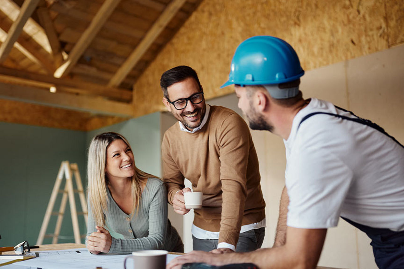 Ein junges Paar mit einem Architekten in einem Rohbau