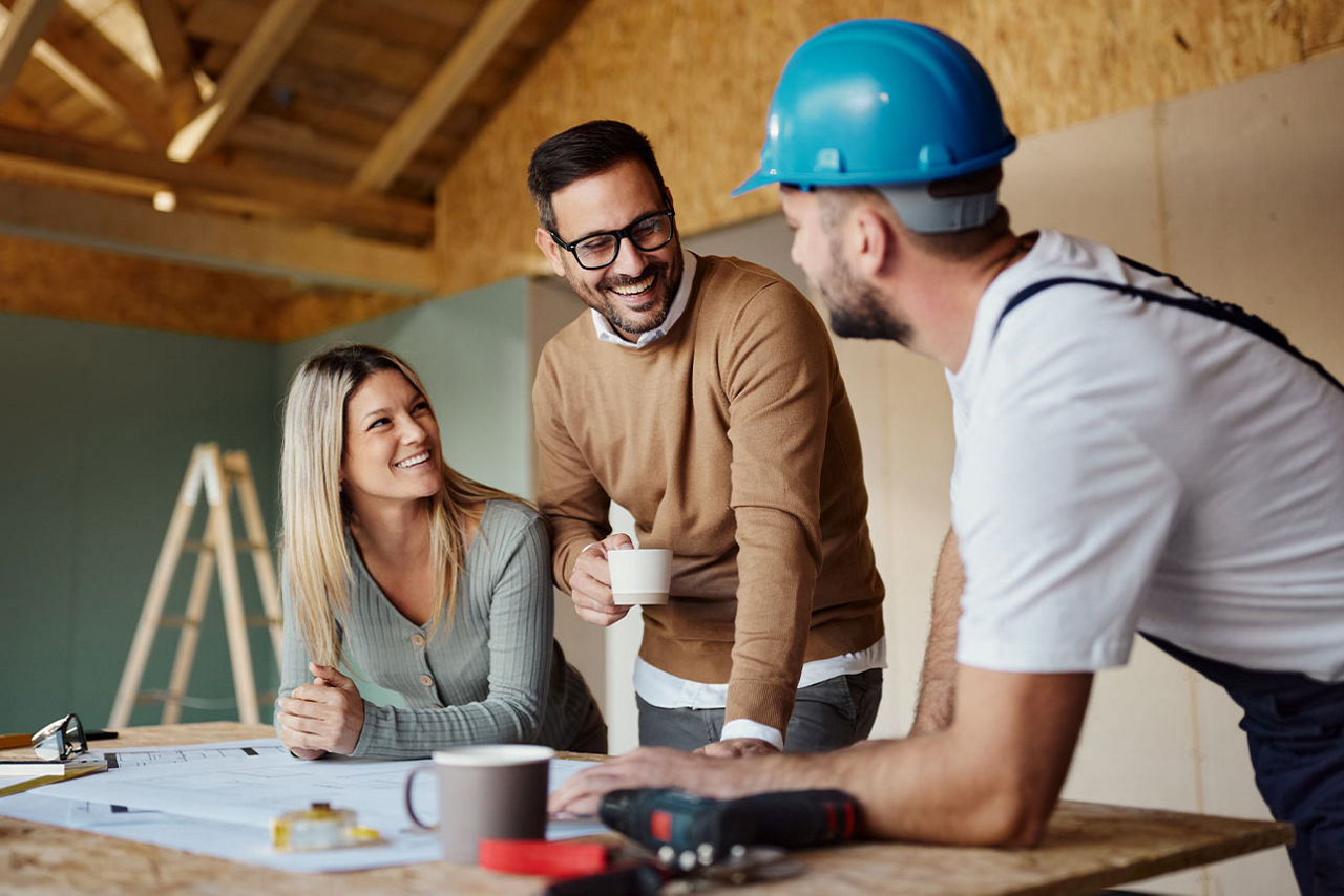 Pärchen spricht mit einem Handwerker auf einer Baustelle