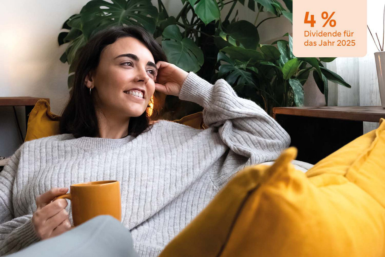 Junge Frau sitzt mit einer Kaffetasse auf ihrer Couch