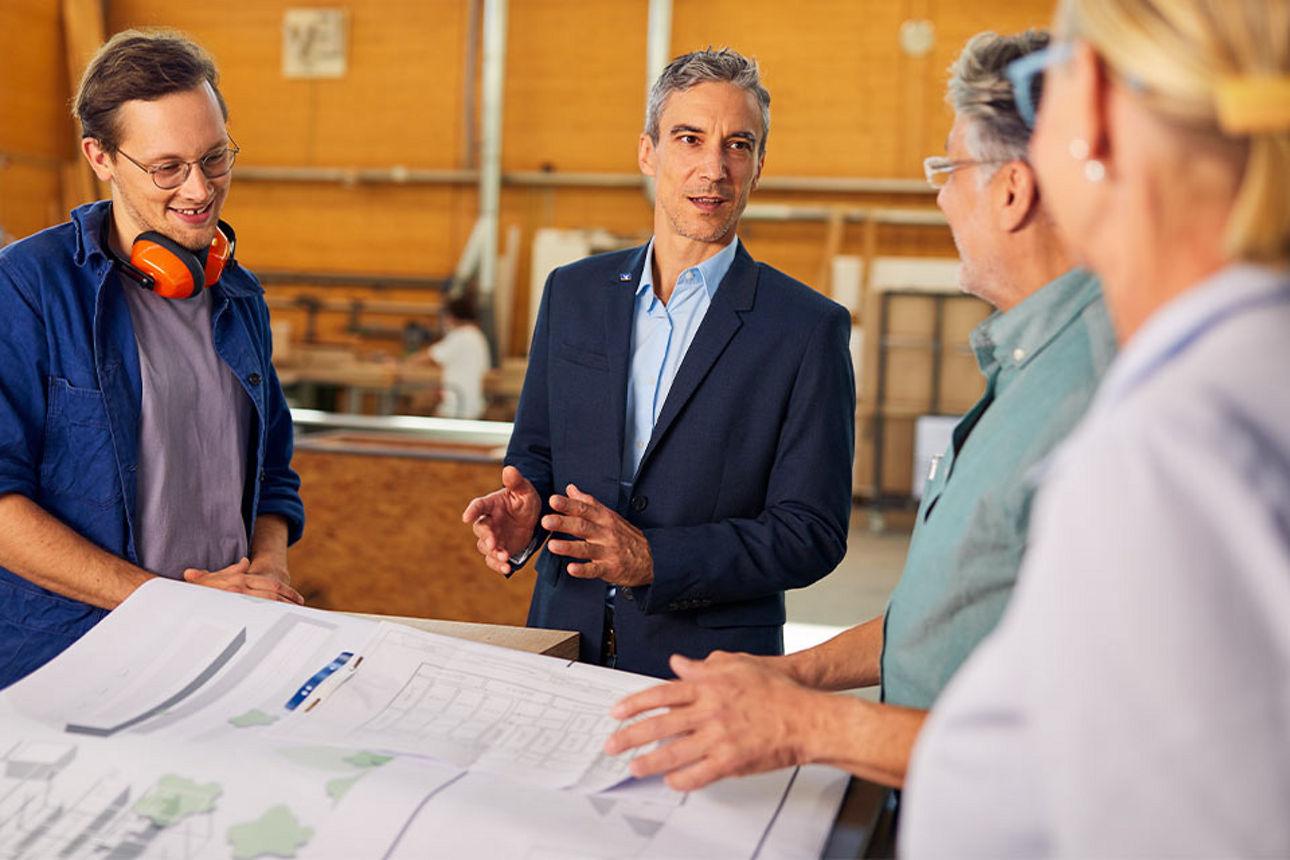 Vier Personen bei einem Gespräch in einer Werkstatt