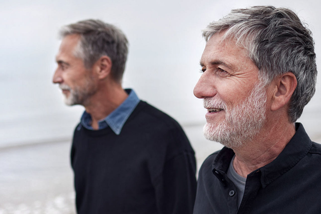 Zwei Männer im Gespräch beim Spaziergang auf dem Strand