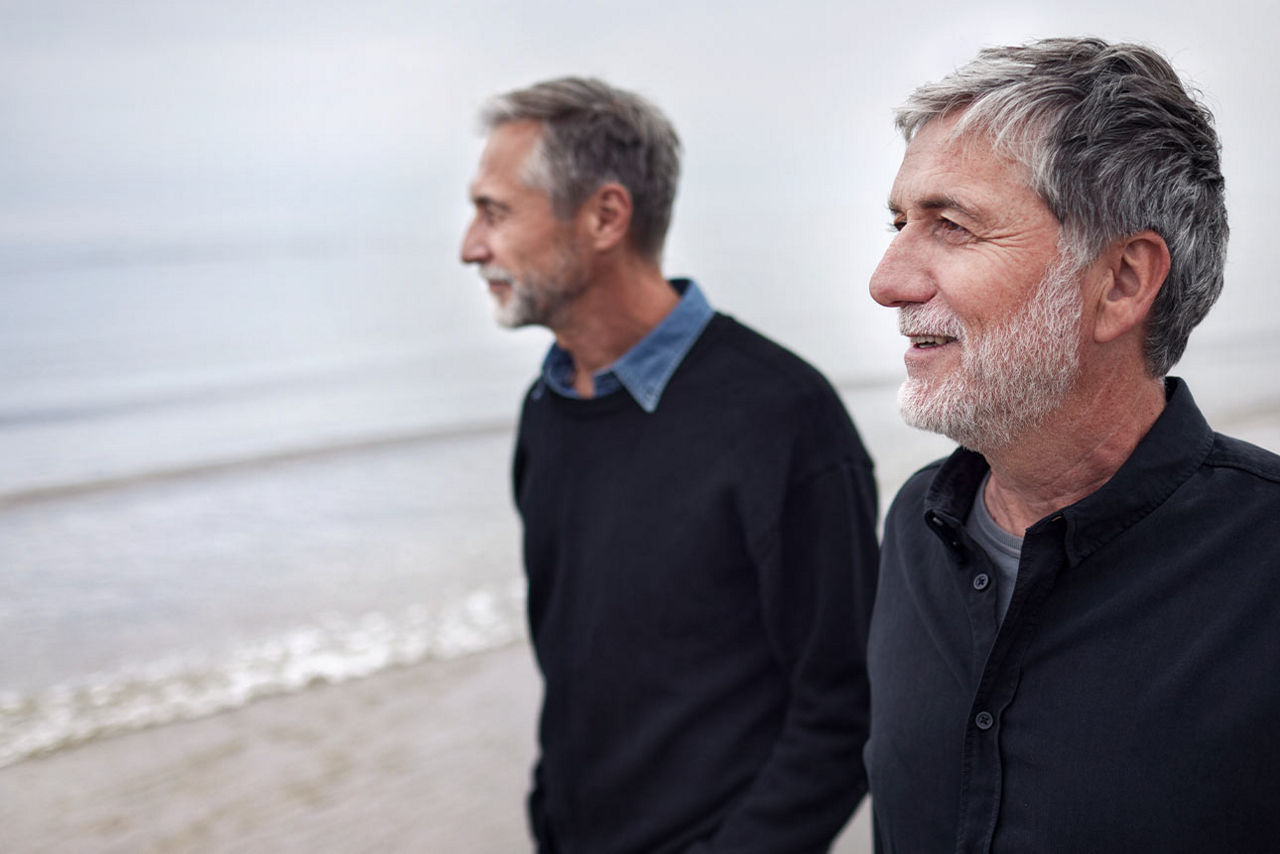 Zwei Männer im Gespräch beim Spaziergang auf dem Strand