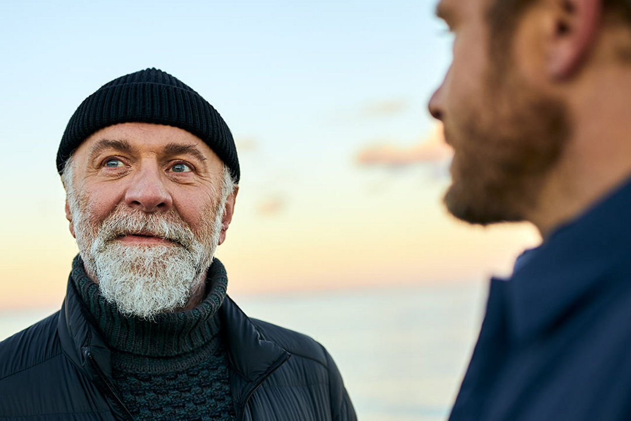 Zwei Männer stehen vor dem Meer und sprechen miteinander