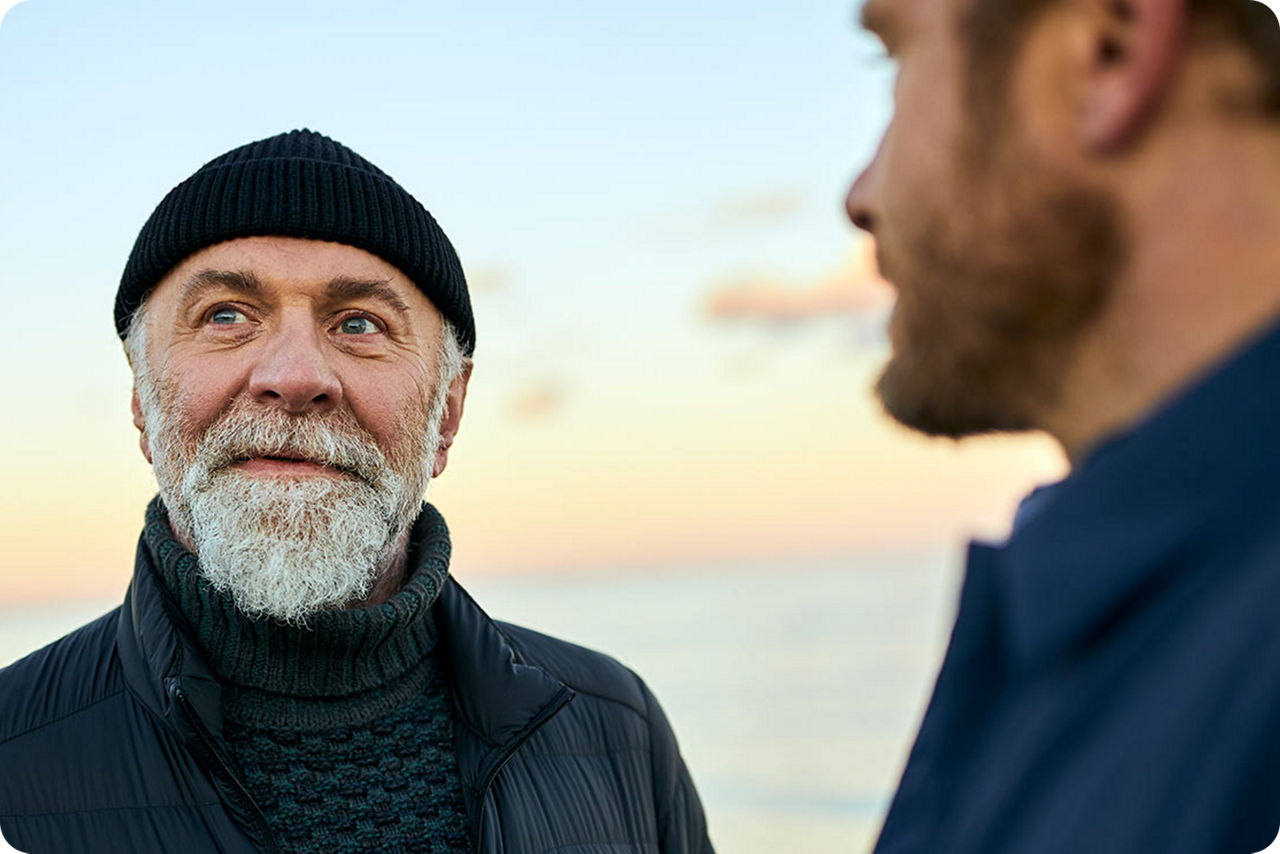 Zwei Männer stehen vor dem Meer und sprechen miteinander