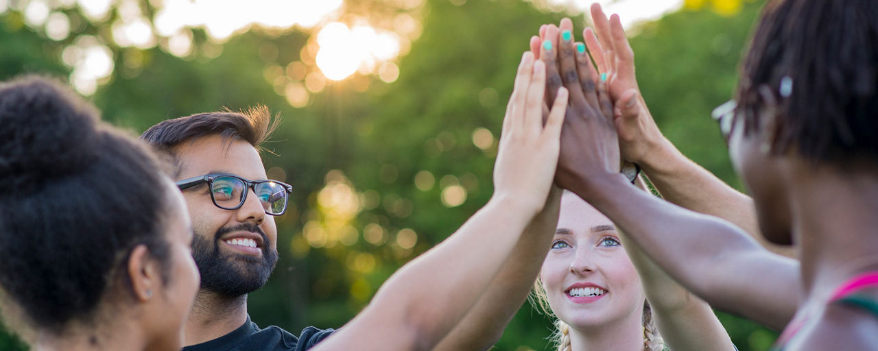 Eine Gruppe von jungen Menschen im Kreis gibt sich eine High-Five in der Mitte