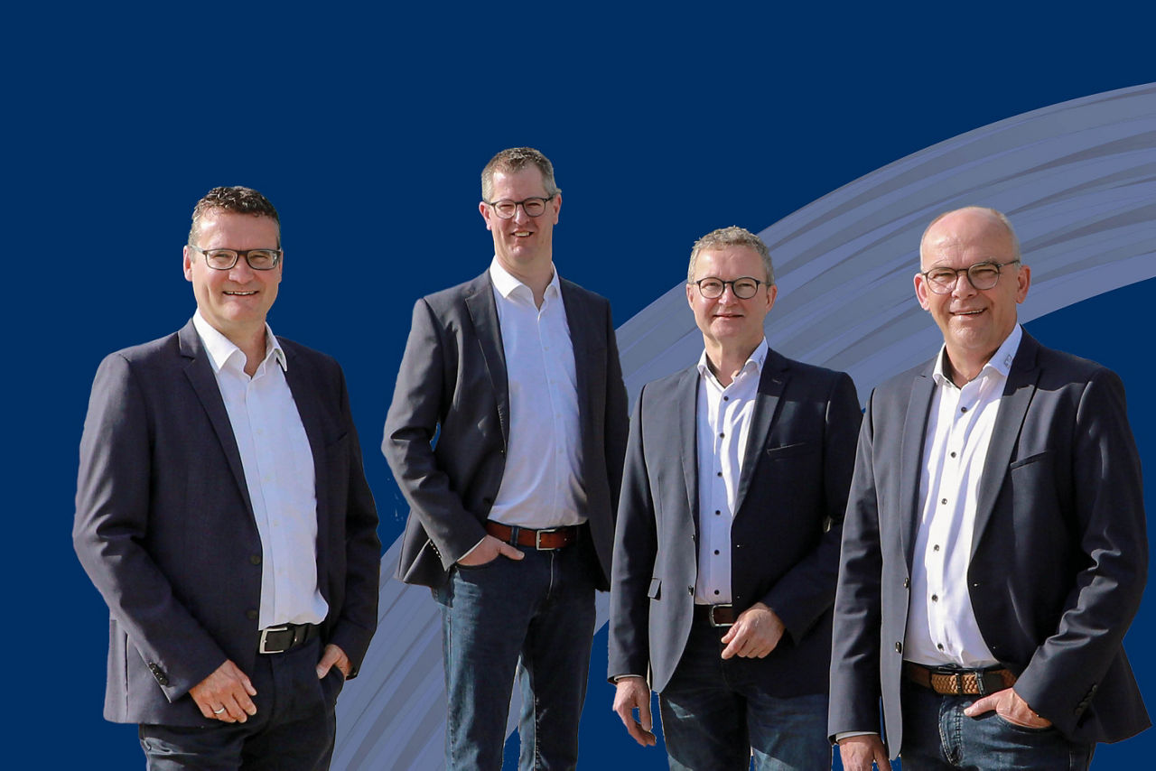 Vier Teammitglieder des Unternehmens, alle in formeller Kleidung und lächelnd.  