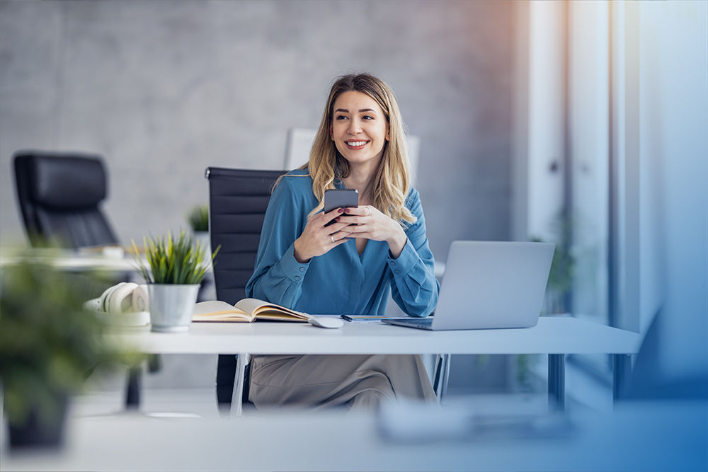 Junge Frau am Schreibtisch mit Smartphone