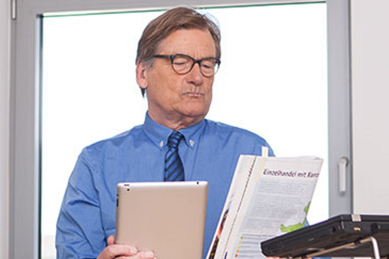 Ein Mann in blauem Hemd und Krawatte steht in einem modernen Büro