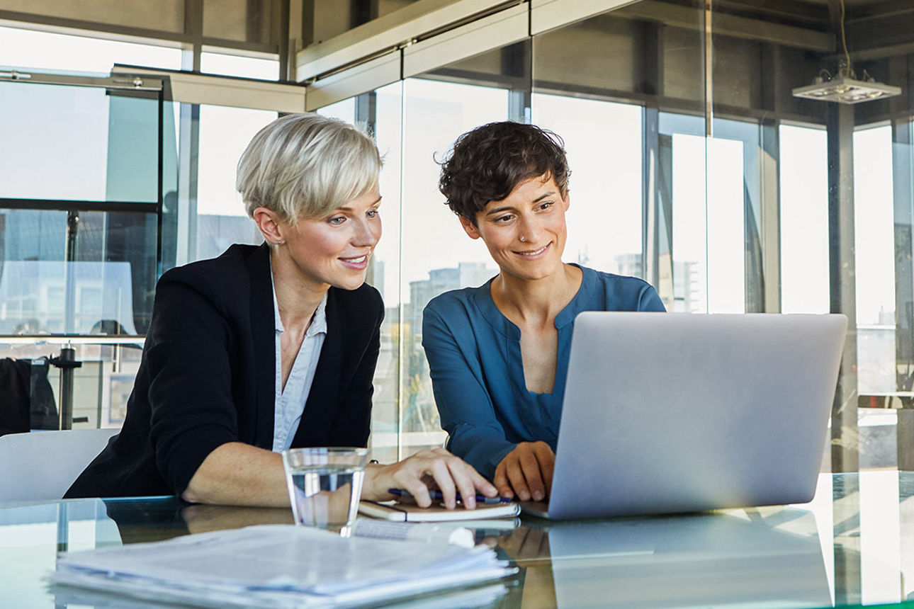 Zwei Frauen sitzen im Büro und arbeiten am Laptop