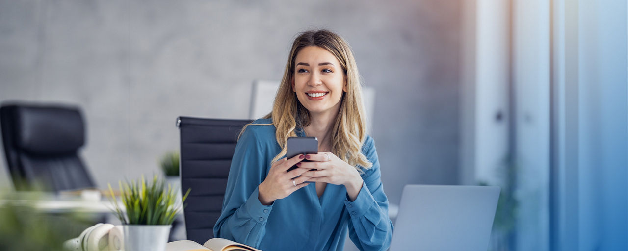 Junge Frau am Schreibtisch mit Smartphone