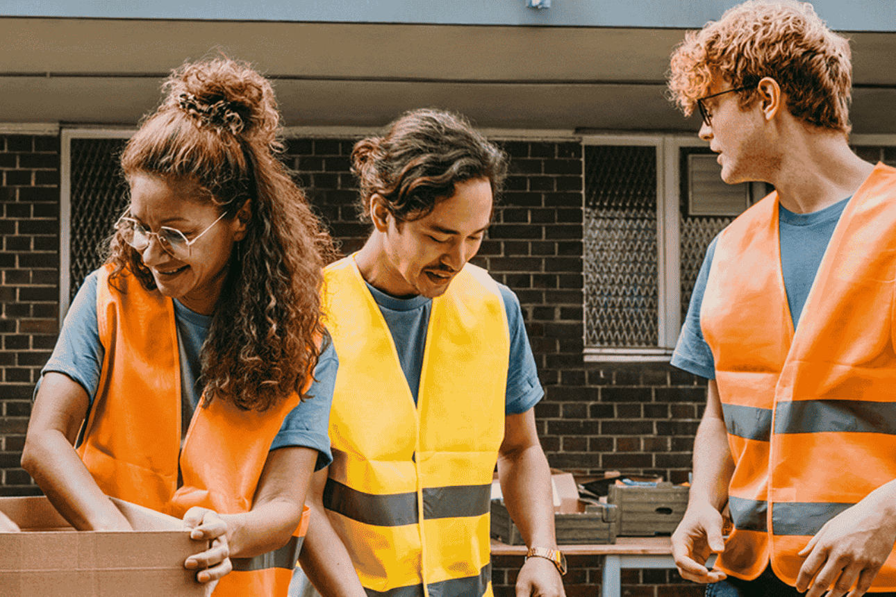 Vier Personen in Warnwesten packen Lebensmittel in Kartons – Einsatz für soziales Engagement.