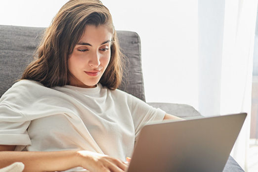 Junge Frau schaut interessiert auf ein Notebook