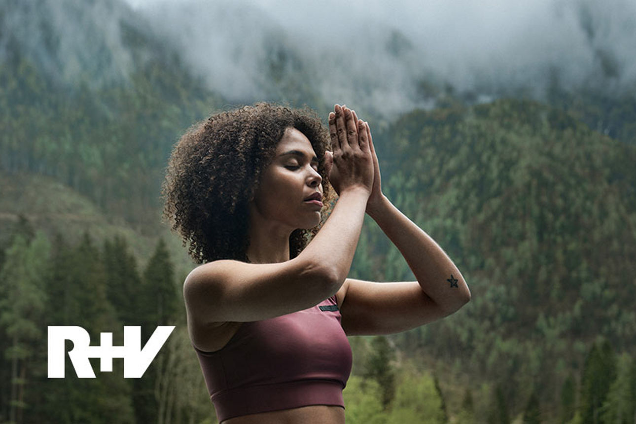 Frau in Yoga-Pose vor einem Bergpanorama