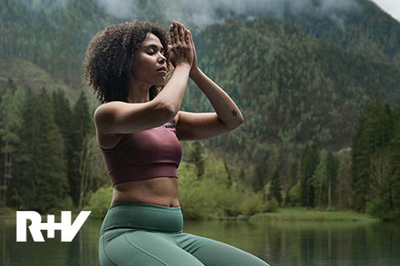 Frau beim Yoga mit See und Bergpanorama im Hintergrund