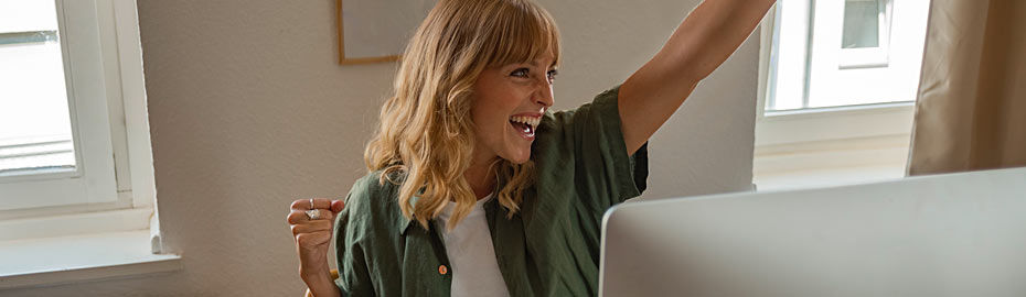 Eine Frau mit langen blonden Haaren sitzt vor einem Laptop