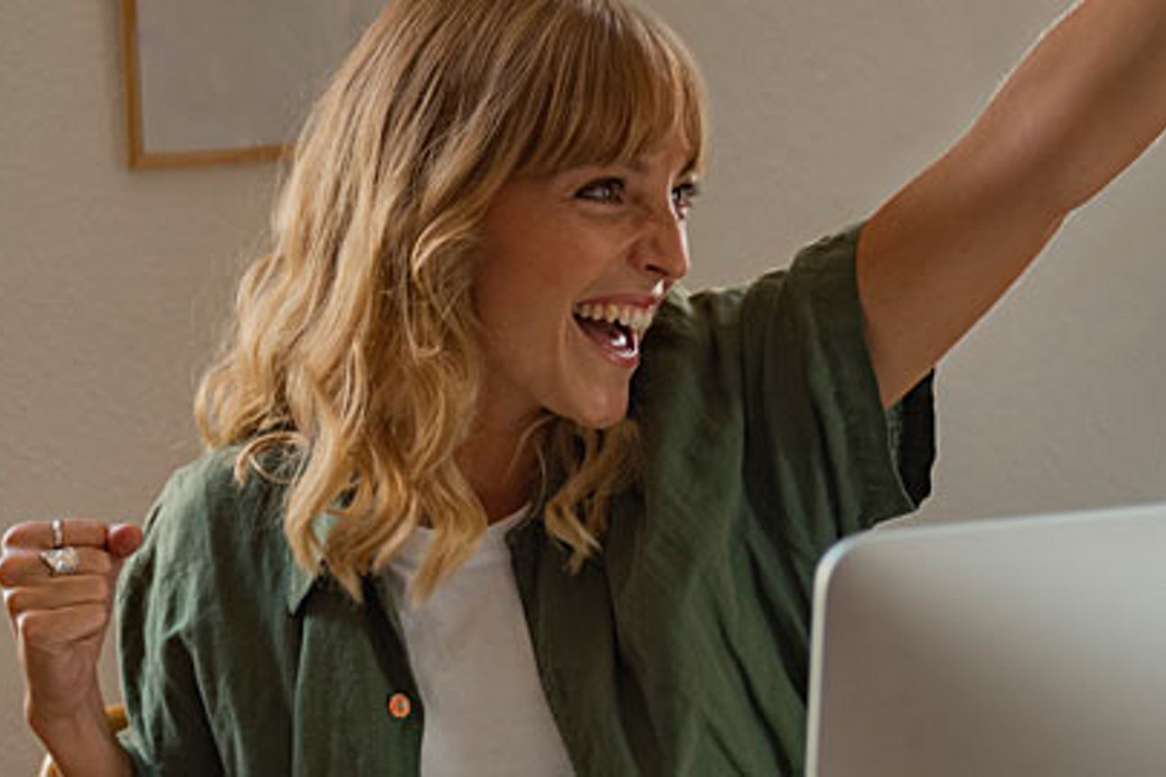 Eine Frau mit langen blonden Haaren sitzt vor einem Laptop