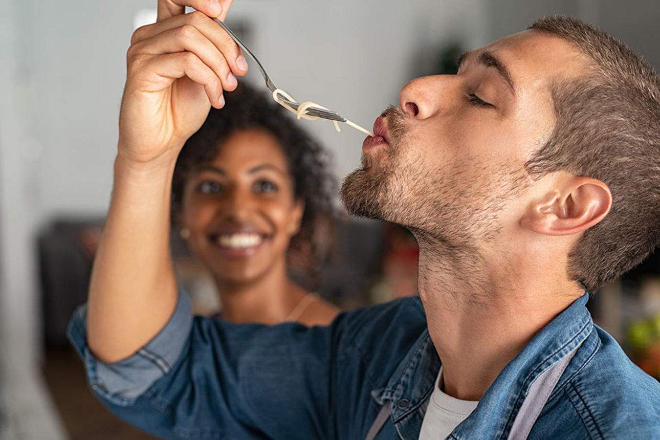 Ein Mann schlürft eine Spaghetti-Nudel von einer Gabel