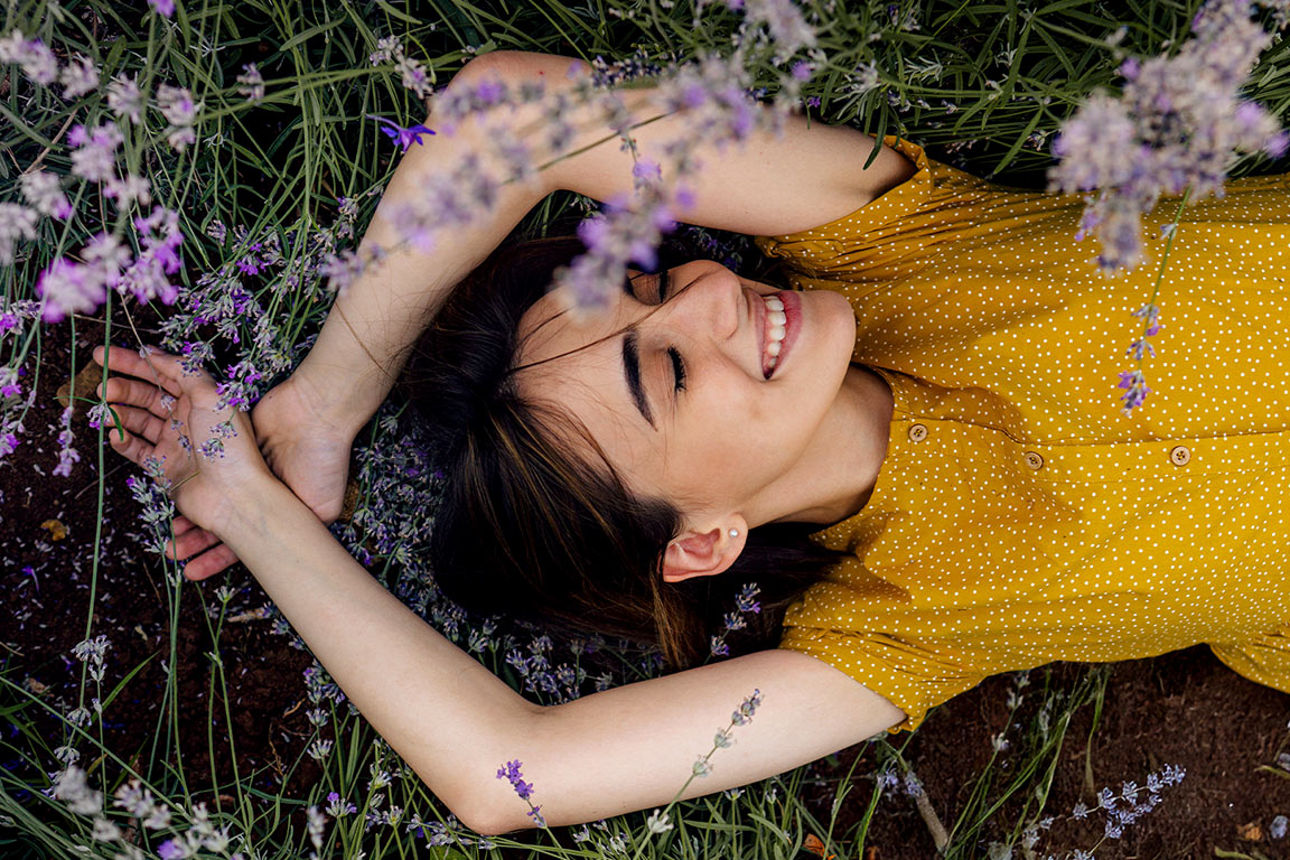 Person mit roter Baskenmütze hält Cappuccino vor einem Café.