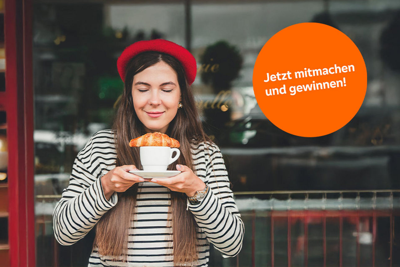 Eine Frau mit Baskenmütze hält ein Croissant und eine Tasse in der Hand