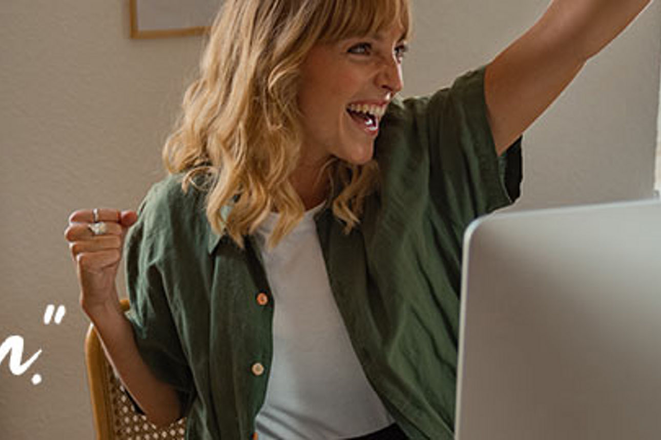 Eine blonde Frau mit einem grünen Hemd hebt vor Freude die linke Hand