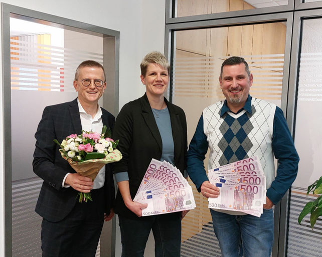 Ein feierlicher Moment wird mit einer Präsentation von Euro-Währung und einem Blumenarrangement festgehalten