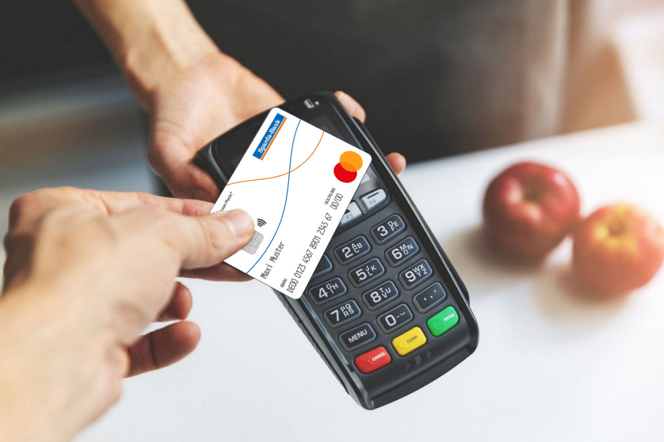 Kontaktloses Bezahlen mit der girocard (Debitkarte), im Hintergrund zwei  Äpfel.