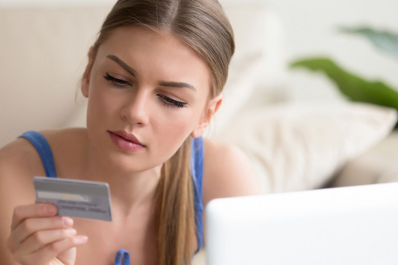 Junge Frau sizt auf dem Sofa und schaut auf ihre girocard