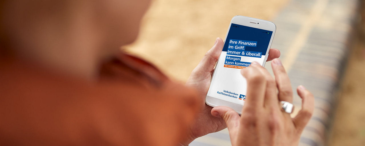 Frau schaut auf die VR Banking App in ihrem Smartphone