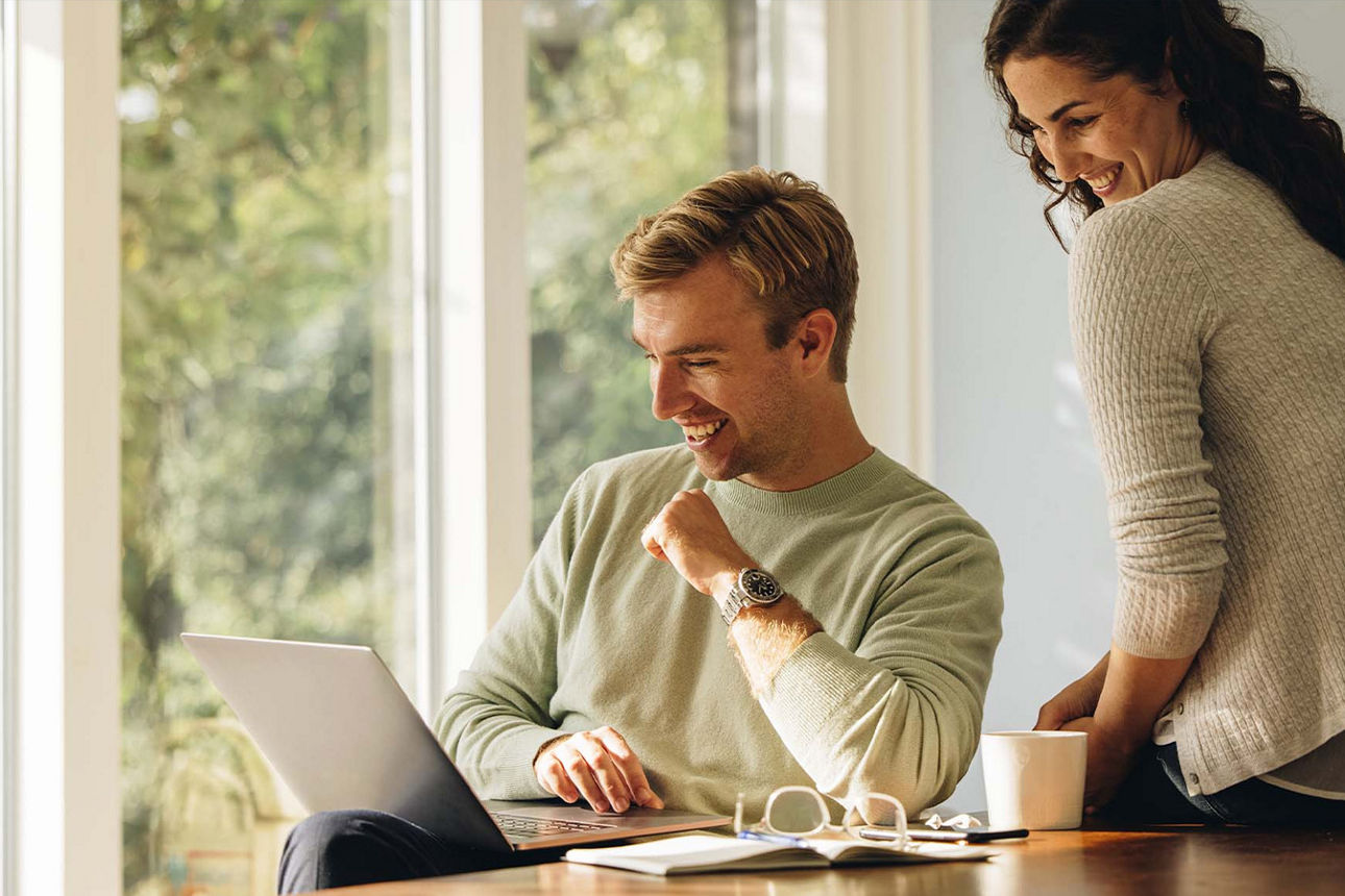 Junges Paar sitzt vor einem Laptop und nutzt unseren digitalen Kontowechselservice