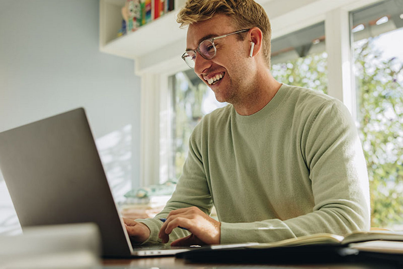 Junger Mann mit Brille sitzt am Laptop
